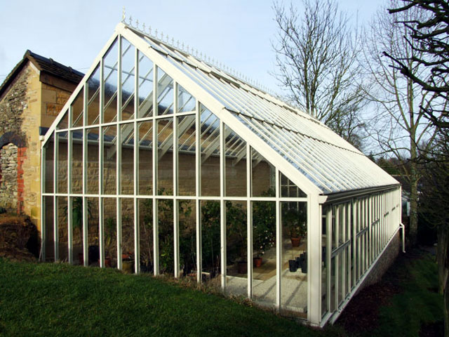 A three quarter span Hartley Lean-to glasshouse build against a stone wall.
